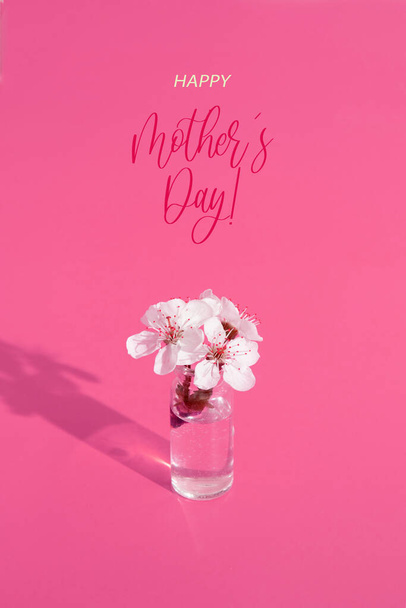 Minyatür cam şişeli ve pembe arka planda çiçekler olan Anneler Günü tebrik kartın kutlu olsun. Dikey biçim. - Fotoğraf, Görsel