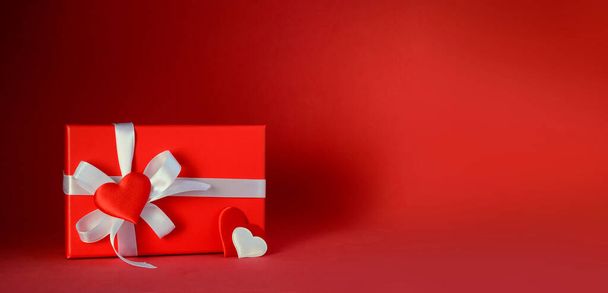 Coffret cadeau rouge avec arc blanc et coeurs sur fond rouge. Cadeau pour la Saint-Valentin, 8 mars, fête des mères, anniversaire. - Photo, image