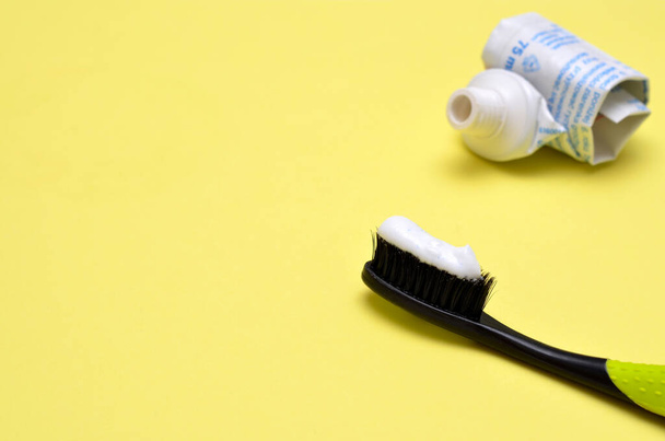 pasta de dientes en un cepillo de dientes y un tubo vacío de pasta de dientes, espacio para copiar - Foto, Imagen