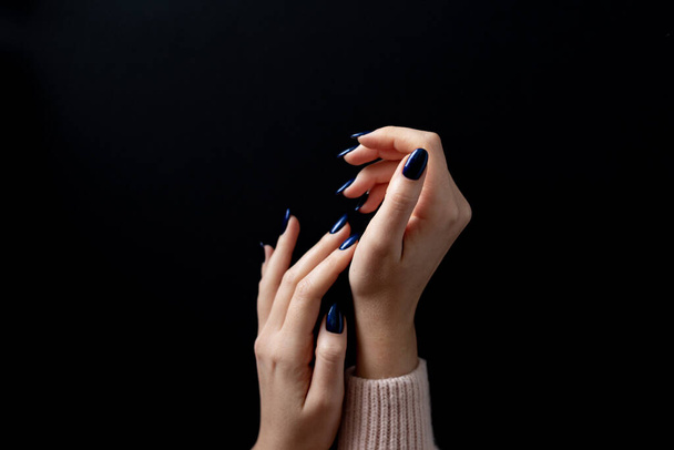 Vrouwen hand met stijlvolle manicure op een zwarte achtergrond. concept voor sociale media. - Foto, afbeelding