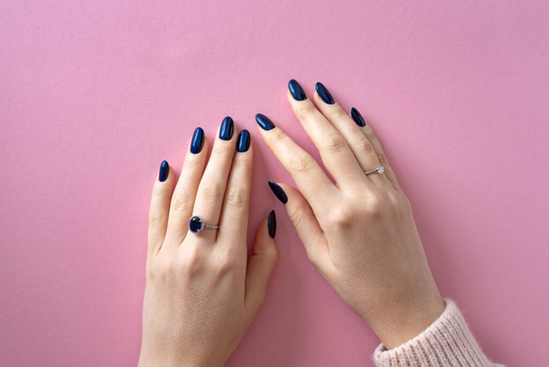 Mooie vrouwelijke handen met blauwe manicure op lange nagels, gel polish coating. - Foto, afbeelding