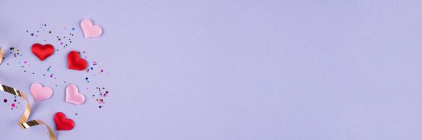 Fondo de banner festivo del día de San Valentín en color moderno del año 2022. Corazones rosados y rojos con confeti multicolor sobre fondo púrpura o violeta con espacio para copiar. Acostado. Vista superior - Foto, Imagen