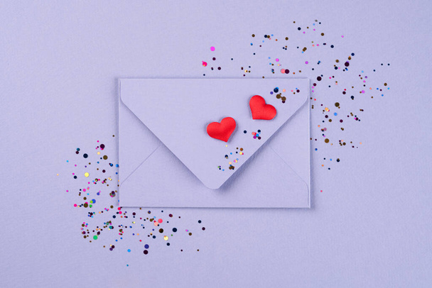 Dia dos Namorados fundo festivo na cor da moda do ano 2022. envelope roxo com corações vermelhos e confete em torno de fundo violeta com espaço de cópia. Deitado plano, vista superior. Cartão de saudação - Foto, Imagem