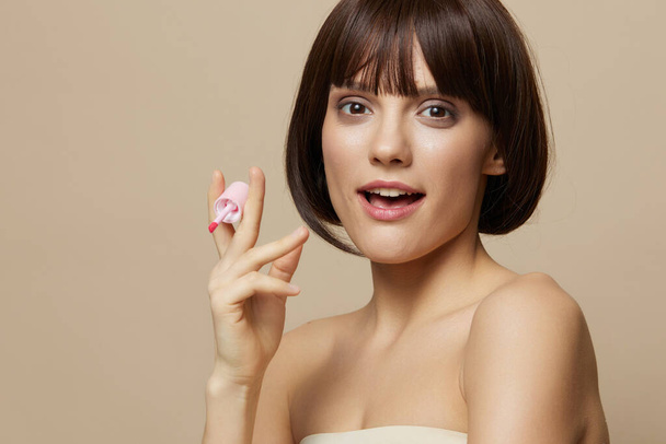 retrato mujer maquillaje lápiz labial en la mano modelo posando primer plano estilo de vida - Foto, imagen
