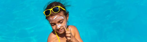 Sunscreen near the pool on the face of the child. Selective focus. - Foto, immagini