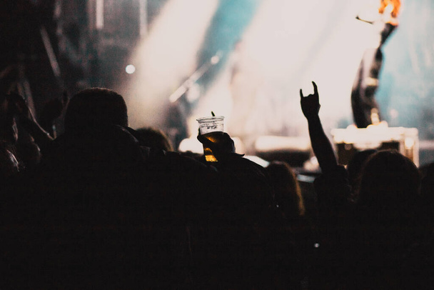 menigte bij concert en silhouetten in podiumlicht - Foto, afbeelding