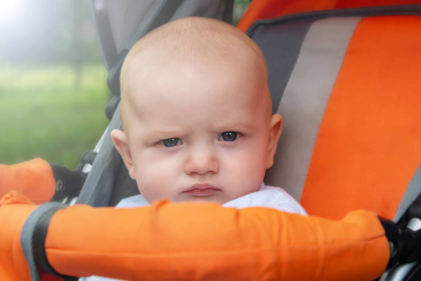 Little boy with serious face in stroller.  - Foto, afbeelding