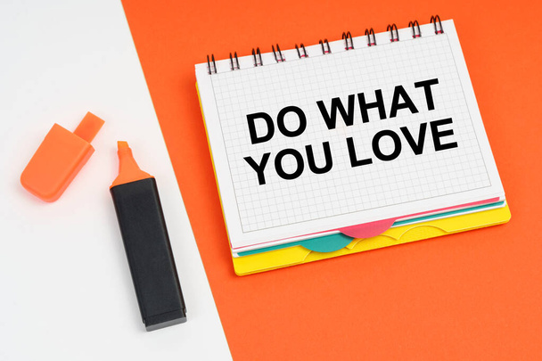 On a white-orange surface lies a marker and a notepad with the inscription - DO WHAT YOU LOVE - Photo, Image