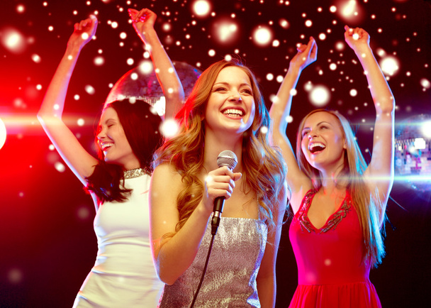 three smiling women dancing and singing karaoke - Fotografie, Obrázek