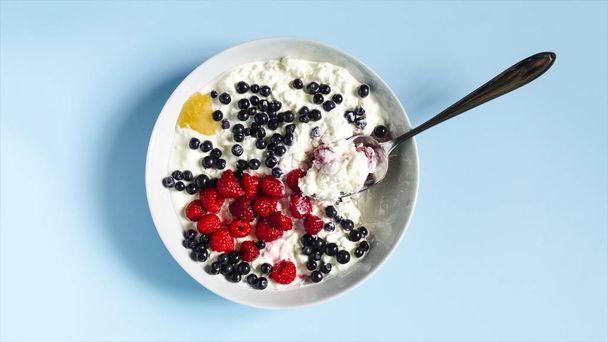The concept of a healthy breakfast. Berries and cottage cheese with sour cream in a light flatley plate - Photo, image