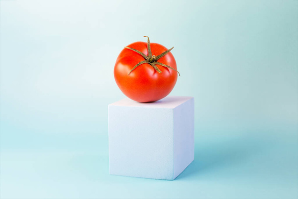 The concept is a bright red tomato on a blue podium top-side view on a blue background. - Fotoğraf, Görsel