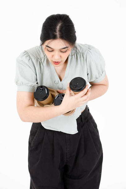 Portrait studio shot of Asian young clumsy teenager female model with ponytail hairstyle wearing casual outfit shocked and surprised when dropping disposable coffee cups holder on white background. - Photo, Image
