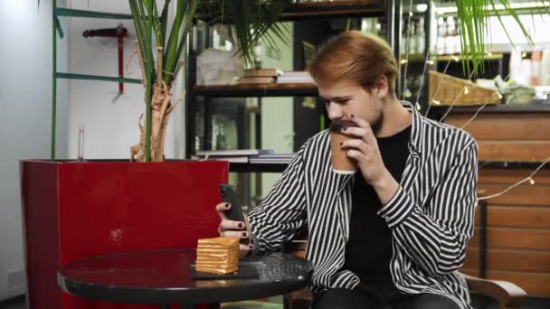 Zbliżenie faceta siedzącego w kawiarni i rozmawiającego przez telefon przez wideo. Kawiarnia - Materiał filmowy, wideo