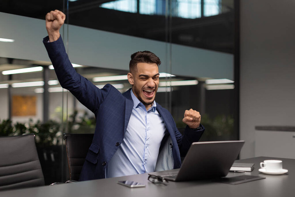 Emocjonalny arabski menedżer świętujący sukces w biurze - Zdjęcie, obraz