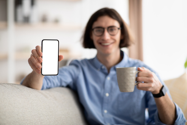 Νεαρός άνδρας δείχνει smartphone με κενή οθόνη, mockup για τη διαφήμισή σας, εφαρμογή ή το σχεδιασμό της ιστοσελίδας, επιλεκτική εστίαση - Φωτογραφία, εικόνα
