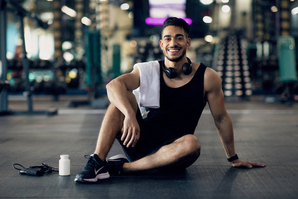młody Arab mężczyzna sportowiec relaks na podłodze po treningu w siłowni - Zdjęcie, obraz