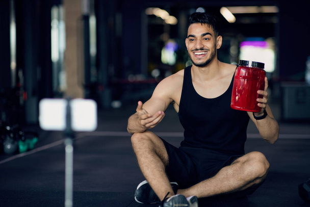 Sportieve jonge Arabische man maken van video beoordeling voor weipoeder op Gym - Foto, afbeelding