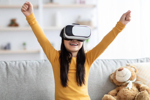 Emotional child teenager using VR glasses, raising hands up - Foto, immagini