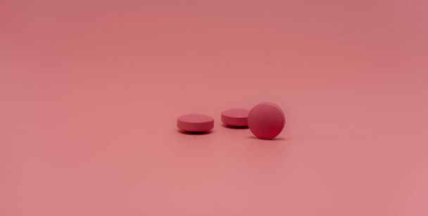 Focus selettivo sulla pillola rotonda rosa compressa su sfondo rosa. Farmacia banner web orizzontale. Industria farmaceutica. Prescrizione di droga. Sfondo della Giornata Mondiale della Salute. Concetto di vitamine e minerali. - Foto, immagini
