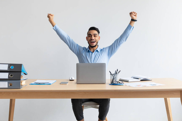 Ενθουσιασμένος άνθρωπος που χρησιμοποιεί φορητό υπολογιστή γιορτάζει την επιτυχία κουνώντας γροθιές - Φωτογραφία, εικόνα