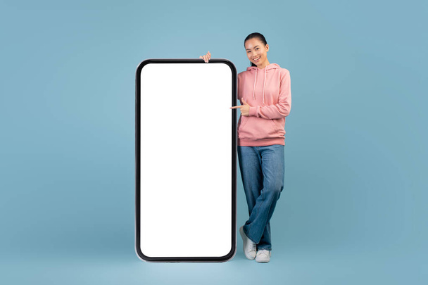 Cheerful korean millennial woman posing with big smartphone - Foto, immagini