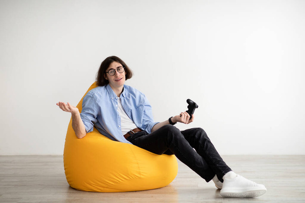 Uomo annoiato seduto in poltrona beanbag con joystick, giocare da solo ai videogiochi e perdere, riposare a casa, spazio libero - Foto, immagini