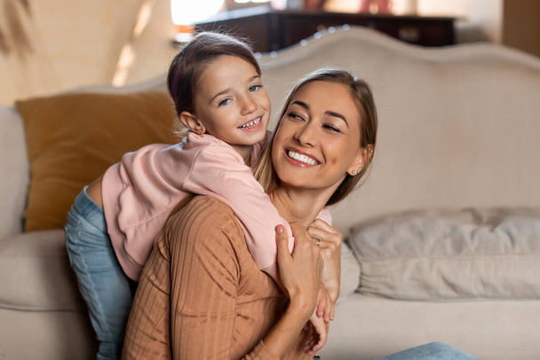 Портрет счастливой мамы и дочери, обнимающихся дома - Фото, изображение