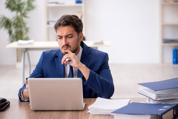 Giovane dipendente maschio infelice con un lavoro eccessivo in ufficio - Foto, immagini