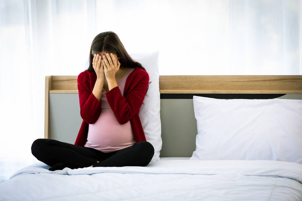 Caucasian millennial young stressed depressed upset worried unhappy lonely female prenatal pregnant mother in casual pregnancy outfit sitting holding hands cover face crying alone on bed in bedroom. - Fotoğraf, Görsel