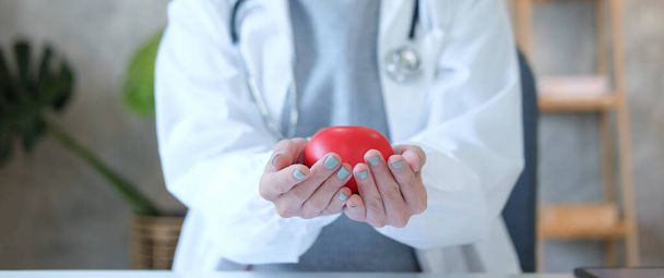赤い心臓を保持聴診器で女性医師の作物のイメージ。心臓病の概念. - 写真・画像