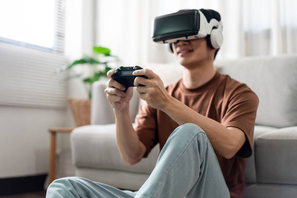 テクノロジーコンセプト仮想現実ヘッドセットを装着し、床に座っている間に黒いコンソールゲームを押す男. - 写真・画像
