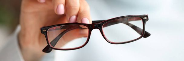En la mano femenina hay unas gafas de estilo a la moda en los marcos negros - Foto, Imagen