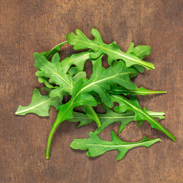 Ruccola leaf on wooden table, pile of fresh green arugula leaves collection top view - Zdjęcie, obraz