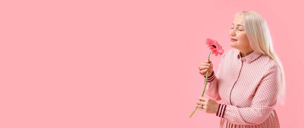 Pembe arka planda aromatik çiçekli, güzel, olgun bir kadın. Uluslararası Kadınlar Günü kutlamaları - Fotoğraf, Görsel