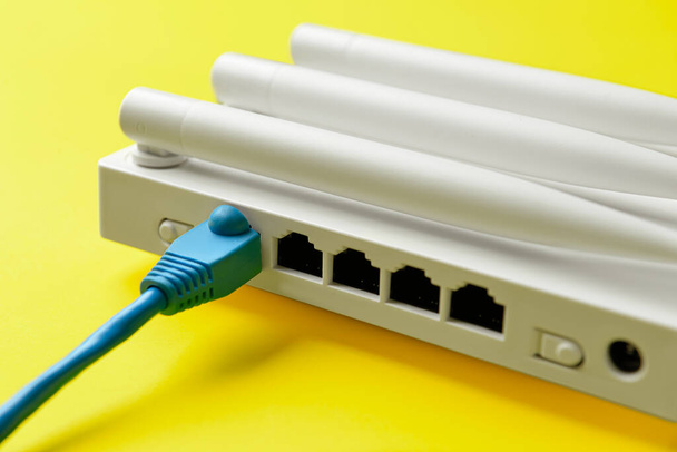 WLAN-Router mit Antennen und Netzwerkkabel auf farbigem Hintergrund - Foto, Bild
