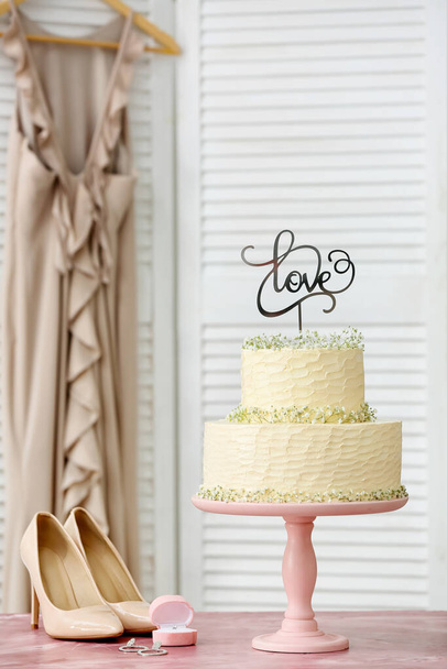 Postre soporte con hermoso pastel de boda y topper con palabra AMOR en la mesa - Foto, Imagen