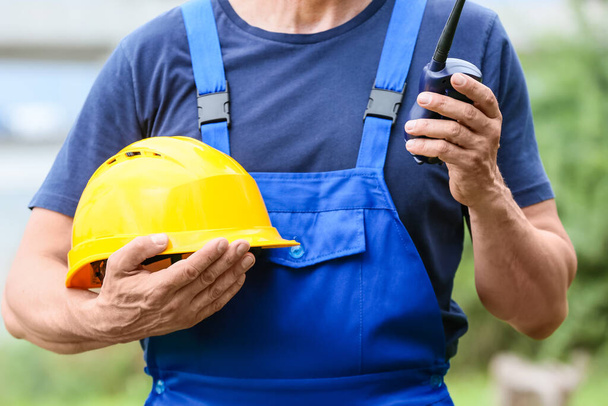 Mannelijke werknemer met veiligheidshelm en radiozender op bouwplaats - Foto, afbeelding