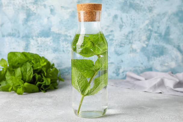 Bottle of water with mint on table - Foto, afbeelding