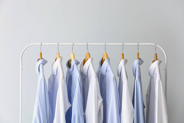Regal mit sauberen Hemden auf grauem Hintergrund - Foto, Bild
