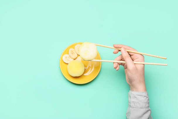 Frau isst köstliche Mochi mit Stäbchen auf farbigem Hintergrund - Foto, Bild