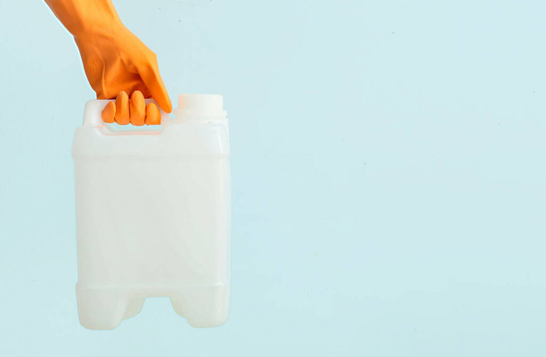 Mano femenina en guantes de goma sosteniendo el recipiente sobre fondo de color - Foto, imagen
