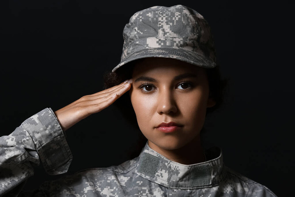 Saluting African-American female soldier on dark background - Photo, image