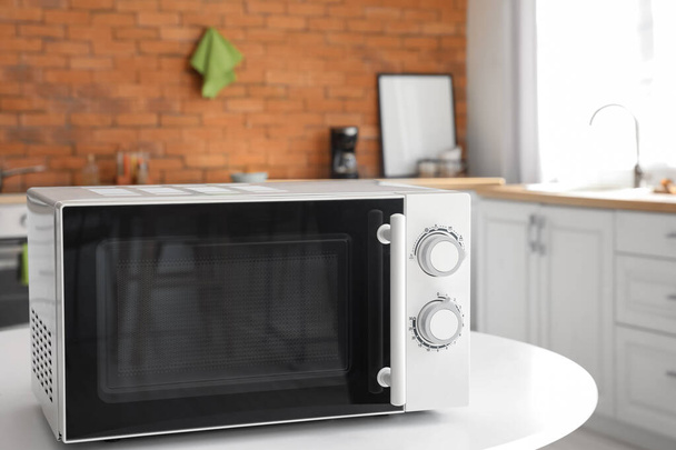 Microwave oven on white table in stylish kitchen - Valokuva, kuva