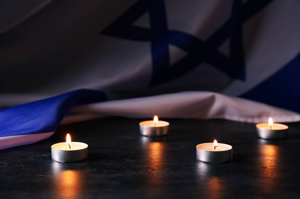 Burning candles and flag of Israel on dark background. Holocaust remembrance day - Photo, Image