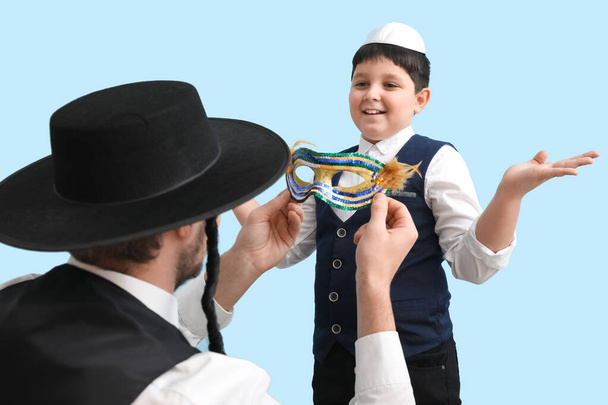 Joodse man en jongen met carnaval masker voor Purim vakantie op kleur achtergrond - Foto, afbeelding