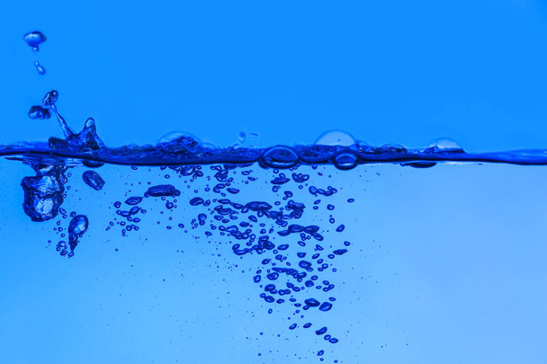 Acqua limpida con bolle d'aria su sfondo blu - Foto, immagini