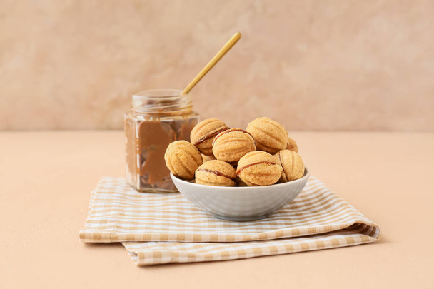 Schaal van smakelijke walnoot vormige koekjes met gekookte gecondenseerde melk op tafel - Foto, afbeelding
