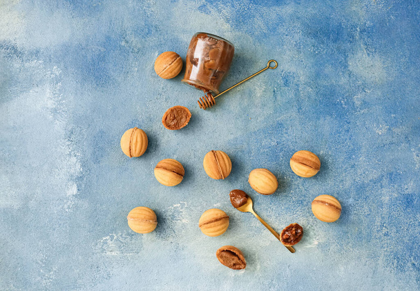 Tasty walnut shaped cookies with boiled condensed milk on blue background - Foto, imagen