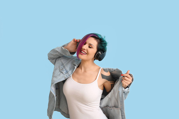 Hermosa mujer con cabello inusual escuchando música sobre fondo azul - Foto, imagen
