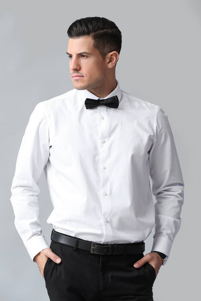 Модный джентльмен держит руки в карманах на сером фоне - Фото, изображение